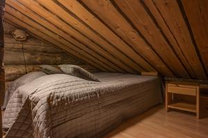a bed in a room with a wooden ceiling at Kuusirinne 2A - a log cabin near the slopes of Ruka in Ruka +4 photos