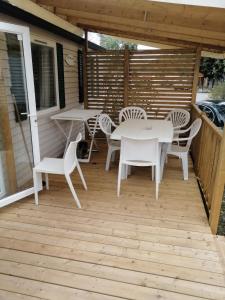 a patio with white tables and chairs on a deck at 2 Mobil home chez Alain in Cadenet
