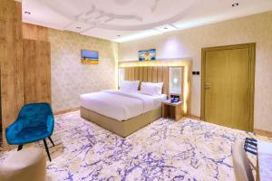 Habitación de hotel con cama y silla azul en Wissam Al-Hawra Hotel en Umm Lajj