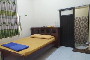 - une petite chambre avec un lit et une douche dans l'établissement OYO 93571 Wisma Air Mancur Homestay, à Malang