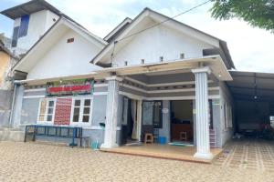 une maison blanche avec terrasse couverte dans une rue dans l'établissement OYO 93571 Wisma Air Mancur Homestay, à Malang