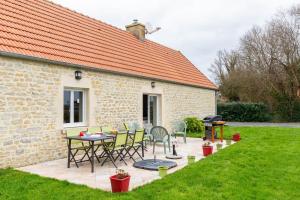 a patio with a table and chairs next to a building at La Pêcherie d'Utah in Audouville-la-Hubert