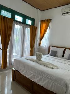 a bedroom with two beds and windows with curtains at Bima Homestay Lembongan in Nusa Lembongan