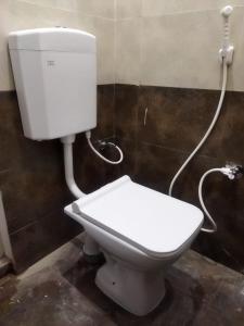 a white toilet in a bathroom with a hose at Rue Heritage inn in Puducherry