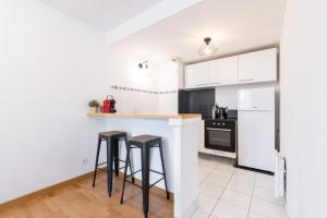 eine Küche mit weißen Schränken und Barhockern in der Unterkunft Euratechnologies - Bright apartment with parking in Lille