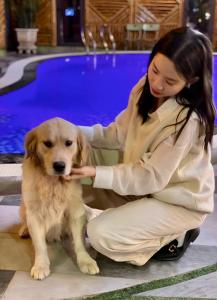 Una mujer acaricia a un perro junto a una piscina. en Cat Ba Rustic Homestay, en Cat Ba