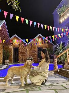 a woman is petting a dog in front of a house at Cat Ba Rustic Homestay in Cat Ba