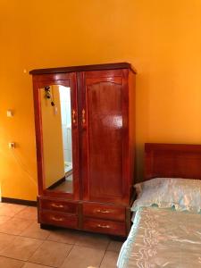 une armoire en bois avec un miroir à côté d'un lit dans l'établissement Logerthine Studio Suriname, à Paramaribo
