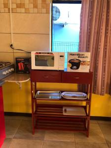 a microwave on a shelf in a kitchen at Logerthine Studio Suriname in Paramaribo