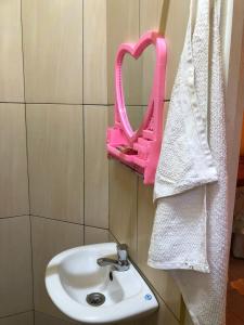 La salle de bains est pourvue d'un lavabo et d'un miroir rose. dans l'établissement Logerthine Studio Suriname, à Paramaribo