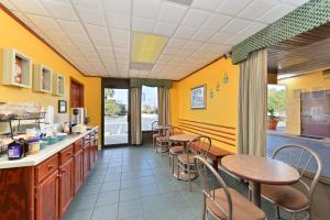 un restaurante con mesas, sillas y paredes amarillas en Americas Best Value Inn St. Augustine, en St. Augustine Beach