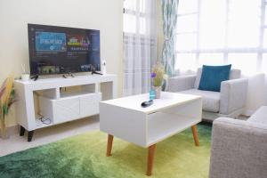ein Wohnzimmer mit einem TV und einem weißen Couchtisch in der Unterkunft Marvel Homes in Meru