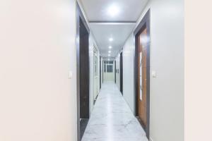 an empty hallway with white walls and a white tile floor at FabExpress Grand Inn I in Lucknow