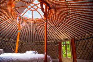 yurta grande con cama y ventana en Glamping El Jardín De Las Delizias Valle Del Jerte, en Casas del Castañar