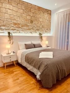 1 dormitorio con 1 cama grande y pared de ladrillo en Apartamento Esencia San Vicente de la Sonsierra en San Vicente de la Sonsierra