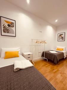 Habitación con 2 camas, paredes blancas y suelo de madera. en Apartamento Esencia San Vicente de la Sonsierra en San Vicente de la Sonsierra