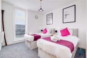 two beds in a white room with pink pillows at City View Apartments in Birmingham