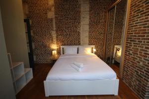a bedroom with a white bed in a brick wall at Old Town - Lovely typical house in Lille