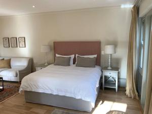 a bedroom with a large white bed and a couch at The Alphen Cottage in Cape Town