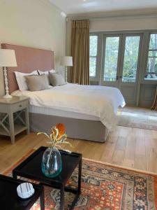 a bedroom with a bed and a vase of flowers on a table at The Alphen Cottage in Cape Town