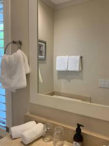 a bathroom with a sink and a mirror and towels at The Alphen Cottage in Cape Town