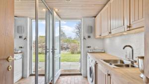 una cocina con fregadero y una puerta a un patio en Hjertevarm Oase: Harmoni og højt til loftet en Morud