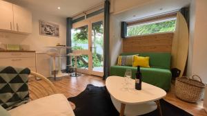 een woonkamer met een tafel en een groene bank bij Le Bungalow in Bonningues-lès-Calais
