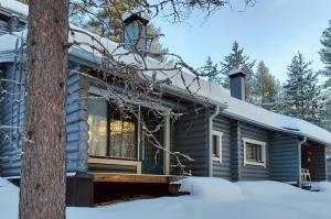 a log cabin in the snow with a tree at Holiday Apartment Lomalaavu D 2 in Suomutunturi