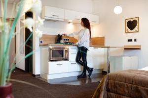 a woman standing in the kitchen in a hotel room at Hotel APARTmenthouse in Rülzheim