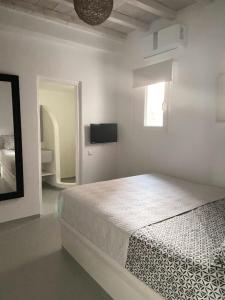 a white bedroom with a bed and a television at Mykonian Luxury Villa Azure w Sea View and Pool in Agios Stefanos