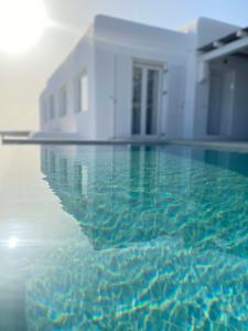una piscina d'acqua di fronte a un edificio di Mykonian Luxury Villa Azure w Sea View and Pool ad Agios Stefanos