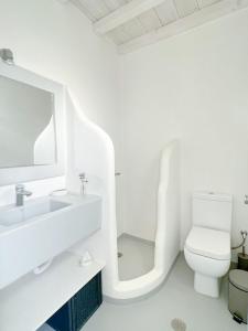 a white bathroom with a toilet and a sink at Mykonian Luxury Villa Azure w Sea View and Pool in Agios Stefanos
