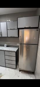 uma cozinha com um frigorífico de aço inoxidável e armários brancos em dreamland em ‘Ezbet `Abd el-Ḥamîd