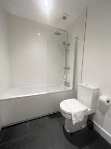 a white bathroom with a toilet and a bath tub at The Gill Townhouse, Ulverston - Lake District in Ulverston