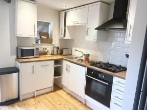 a kitchen with white cabinets and a stove top oven at The Gill Townhouse, Ulverston - Lake District in Ulverston