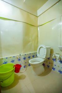 a bathroom with a toilet and a green bucket at Hotel Victoria Inn (Nazimuddin Road) in Dhaka