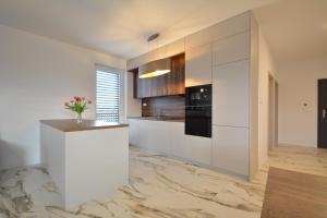 a kitchen with white cabinets and a counter with flowers on it at Apartments Sered in Seredʼ