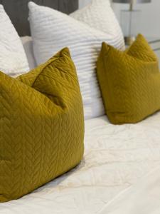 Luxury en-suite in modern house في Catford: سرير مع وسائد صفراء ووسائد بيضاء