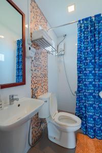 a bathroom with a white toilet and a sink at Bay Area Lodge in Coron