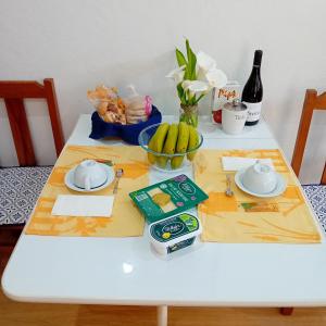 a white table with a bowl of bananas and a bottle of wine at Casinha do Solar in Angra do Heroísmo