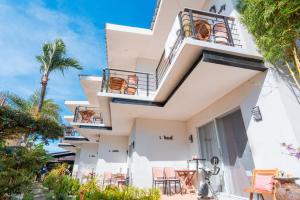 a white building with balconies and tables and chairs at Bay Area Lodge in Coron