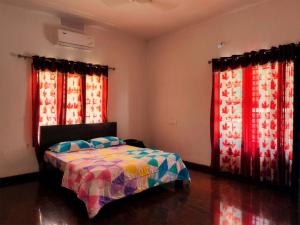 1 dormitorio con 1 cama y 2 ventanas grandes en Thevitisvillas, en Sultan Bathery