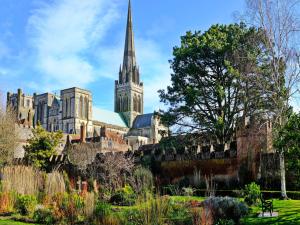 a cathedral with a spire and a garden in the foreground at Pass the Keys Central Modern Flat with Parking in Chichester