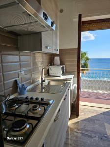 a kitchen with a stove and a view of the ocean at BAGLIO SUL MARE Letojanni Taormina in Letojanni