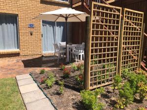 a wooden fence with an umbrella in a garden at Shearwater 106 in Sedgefield