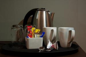 a tray with a coffee pot and cups on a table at Hendersons Lodge Ltd in Senekal