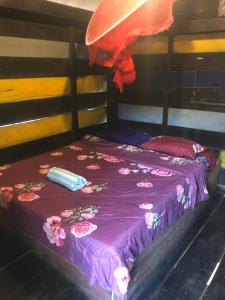 a bed with a purple blanket with flowers on it at New Happy Elephant Bungalows 