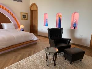 1 dormitorio con 1 cama y 1 silla en Lazib Inn Resort & Spa en ‘Izbat an Nāmūs