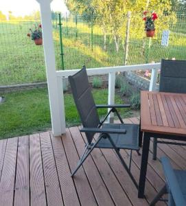 a black chair and a table on a porch at Domki 7 Houses Rewal in Rewal