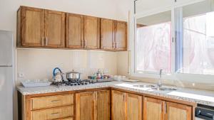cocina con armarios de madera, fregadero y ventana en Airport Apartment M&A, en Nador